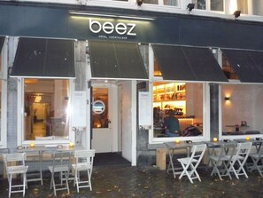 An outdoor seating area with tables and chairs in front of a building with a 'beez' sign. - Hotel Beez (Maastricht)