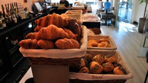 Een bakkerijvitrine met diverse gebakken producten, waaronder croissants en broodjes, in een café.
