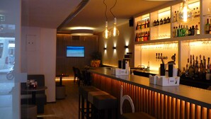 Een moderne bar met een houten toog, zitplaatsen en een televisiescherm.