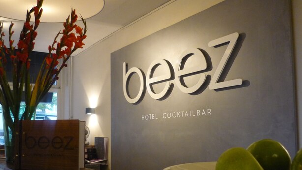 Een hotelcocktailbar genaamd 'beez' met een modern design, een receptiebalie en een schaal fruit op de toonbank.