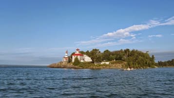 Standing tall on a serene island, a historic lighthouse and charming building offer breathtaking views of the surrounding waters and lush greenery.