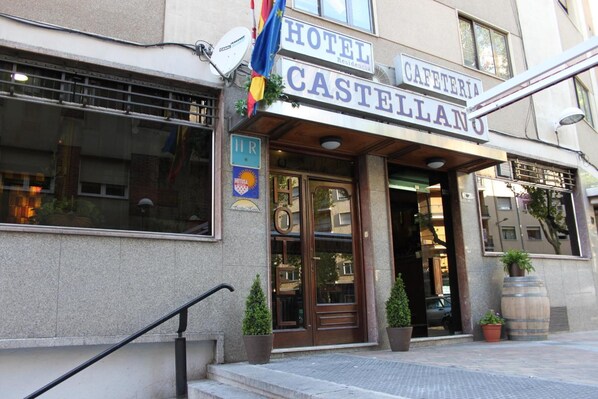 Entrada de un hotel con un cartel que dice 'HOTEL CASTELLANO' y 'CAFETERÍA'.