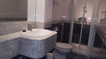 Une salle de bain avec un lavabo, des toilettes et une douche.