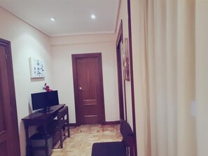 Un couloir avec une porte en bois, un bureau avec un ordinateur et une chaise.