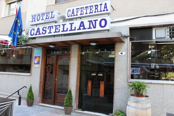 Entrada de um hotel com uma placa que diz "HOTEL CASTELLANO CAFETERIA".