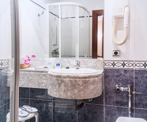 Une salle de bain avec un lavabo en marbre, une cabine de douche en verre et un porte-serviettes.