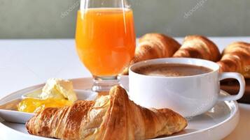 Bandeja de desayuno con cruasanes, jugo de naranja, mantequilla y café.