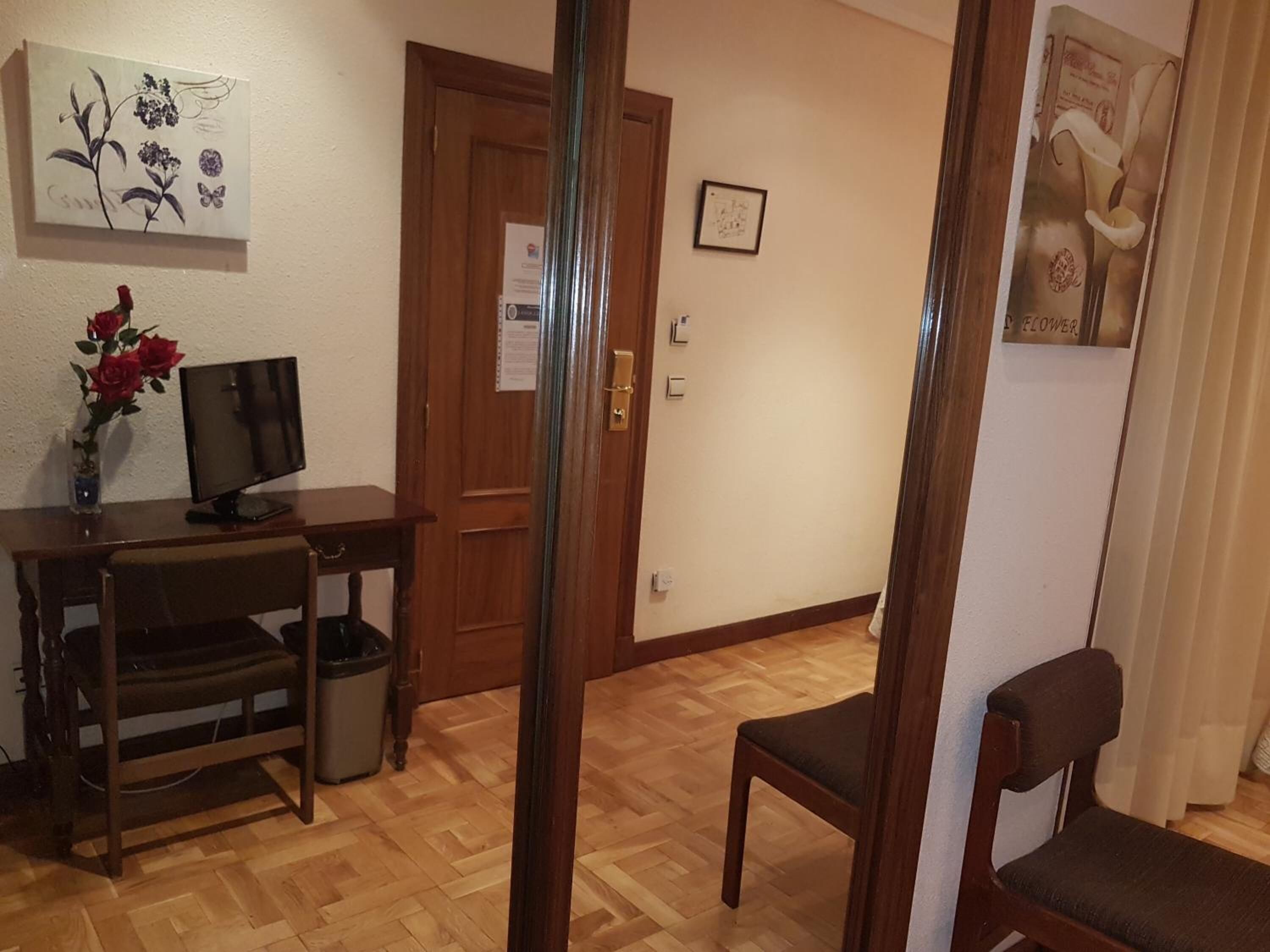 Une pièce comprenant un bureau en bois, un ordinateur, une chaise, une poubelle et une porte.