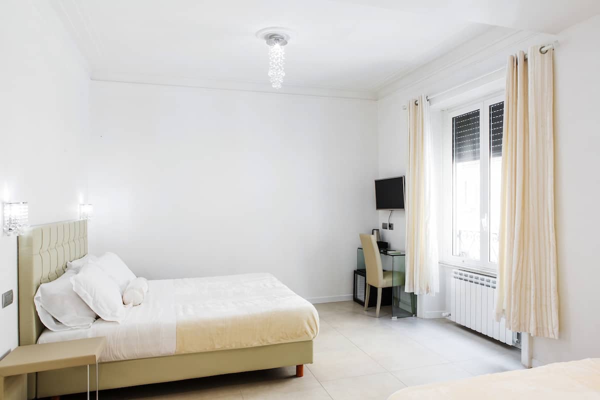 A bedroom with a bed, a desk, and a chair.