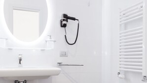 Et moderne badeværelse med hvid vask, pissoir og toilet.