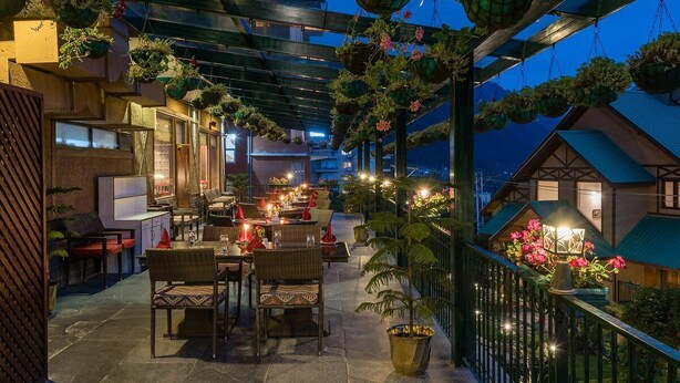 Un espace extérieur aménagé pour les repas, avec des meubles en osier et des jardinières suspendues.