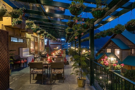 An outdoor dining area with wicker furniture and hanging planters.