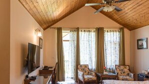 Une chambre avec un plafond en bois, un lit, deux chaises, un bureau et un téléviseur.