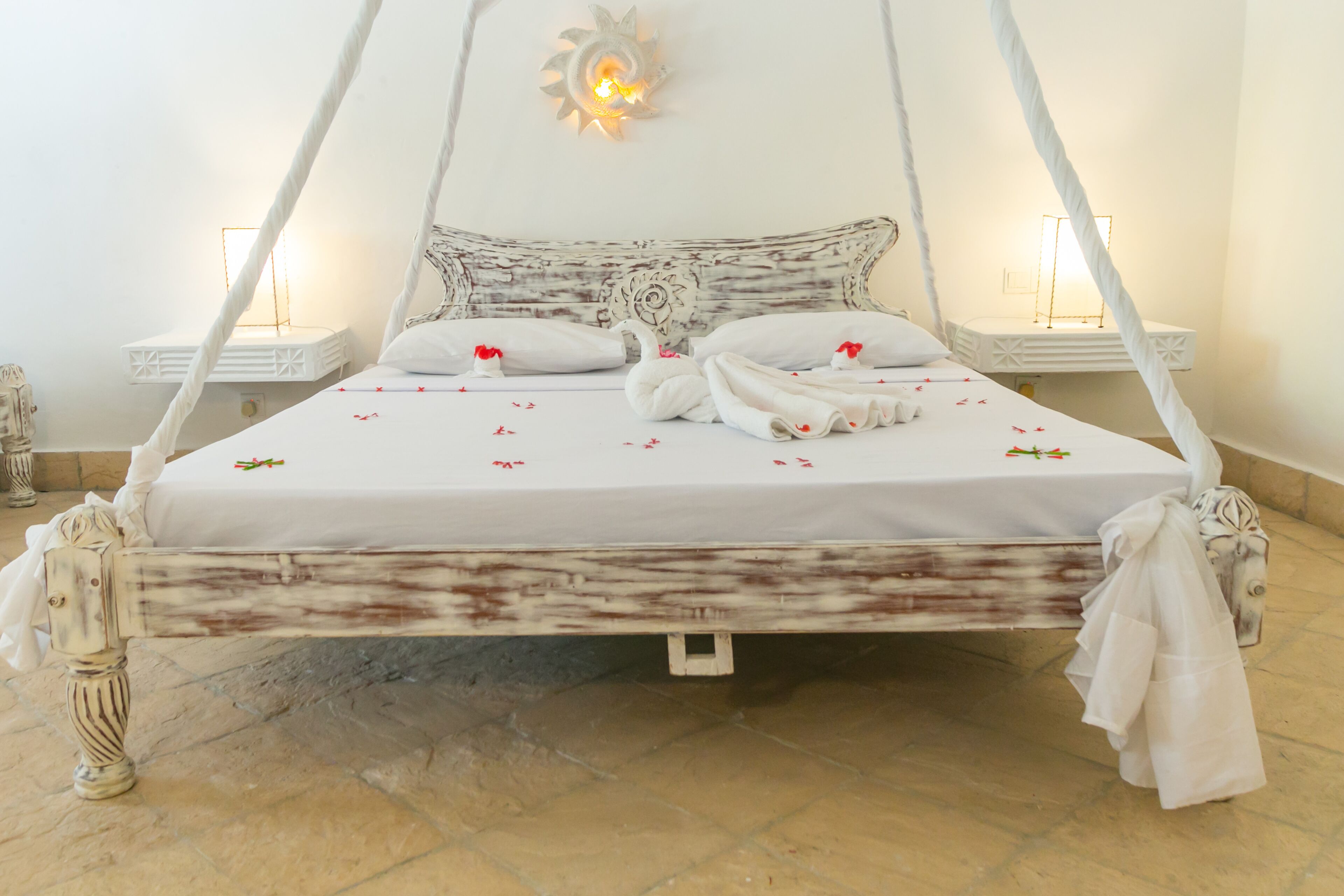 A bed with a canopy, white linens, and decorative pillows.