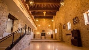 Un interior espacioso con una escalera de madera, paredes de piedra y un suelo pulido.