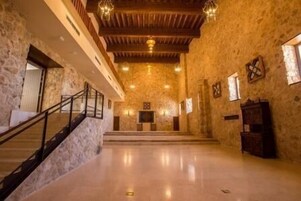 Un interior espacioso con una escalera de madera, paredes de piedra y un suelo pulido.