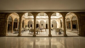 Un amplio patio con múltiples arcos y columnas, que incluye una zona de estar central con mesas y sillas.