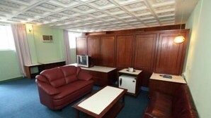 A compact living space with a sofa, a small table, a television, and a cabinet. - Hotel Lotte (Ipoh)