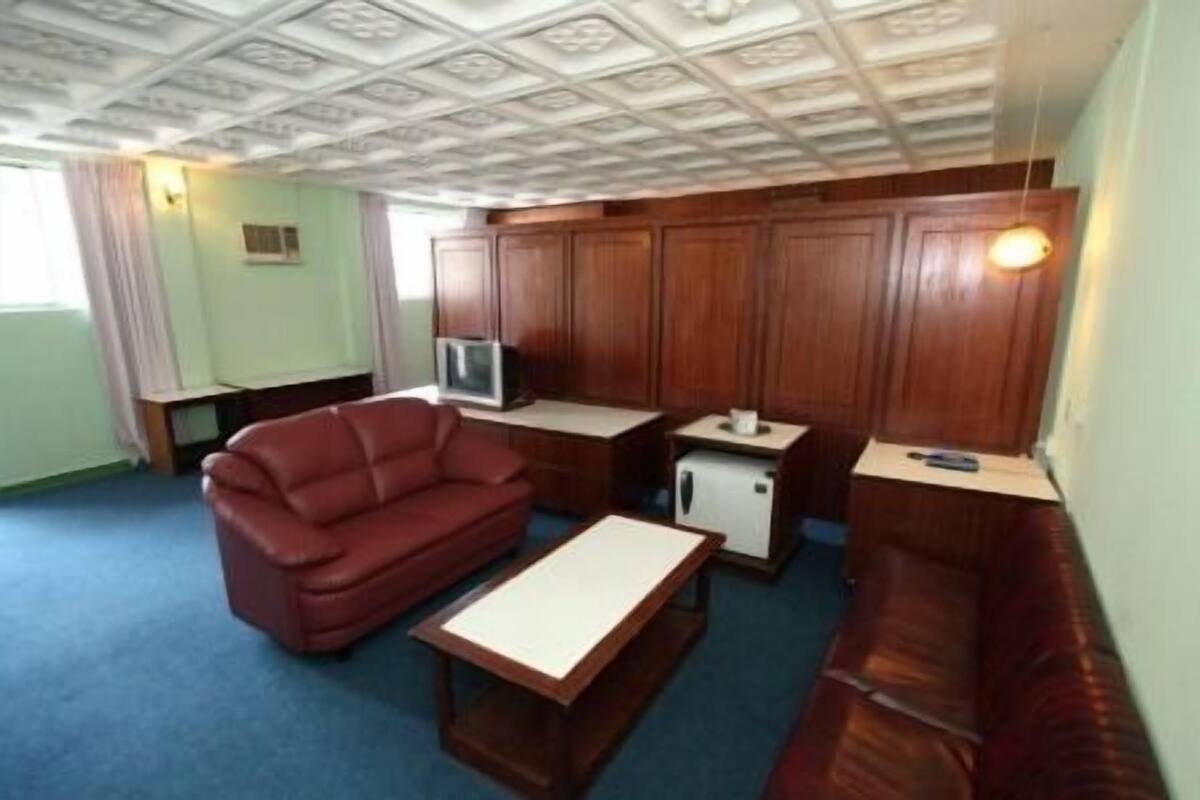 A compact living space with a sofa, a small table, a television, and a cabinet.