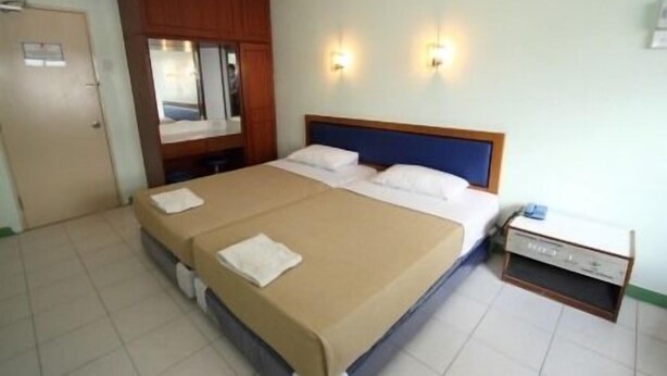 A hotel room with a large bed, a wooden wardrobe, two wall-mounted lights, and a small bedside table. - Hotel Lotte (Ipoh)