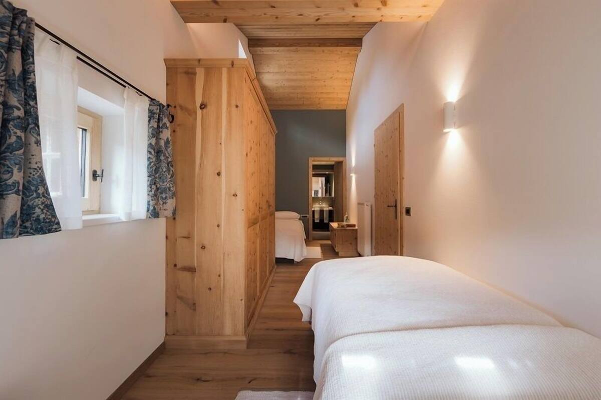 A narrow hallway with wooden walls and a bed on the right.
