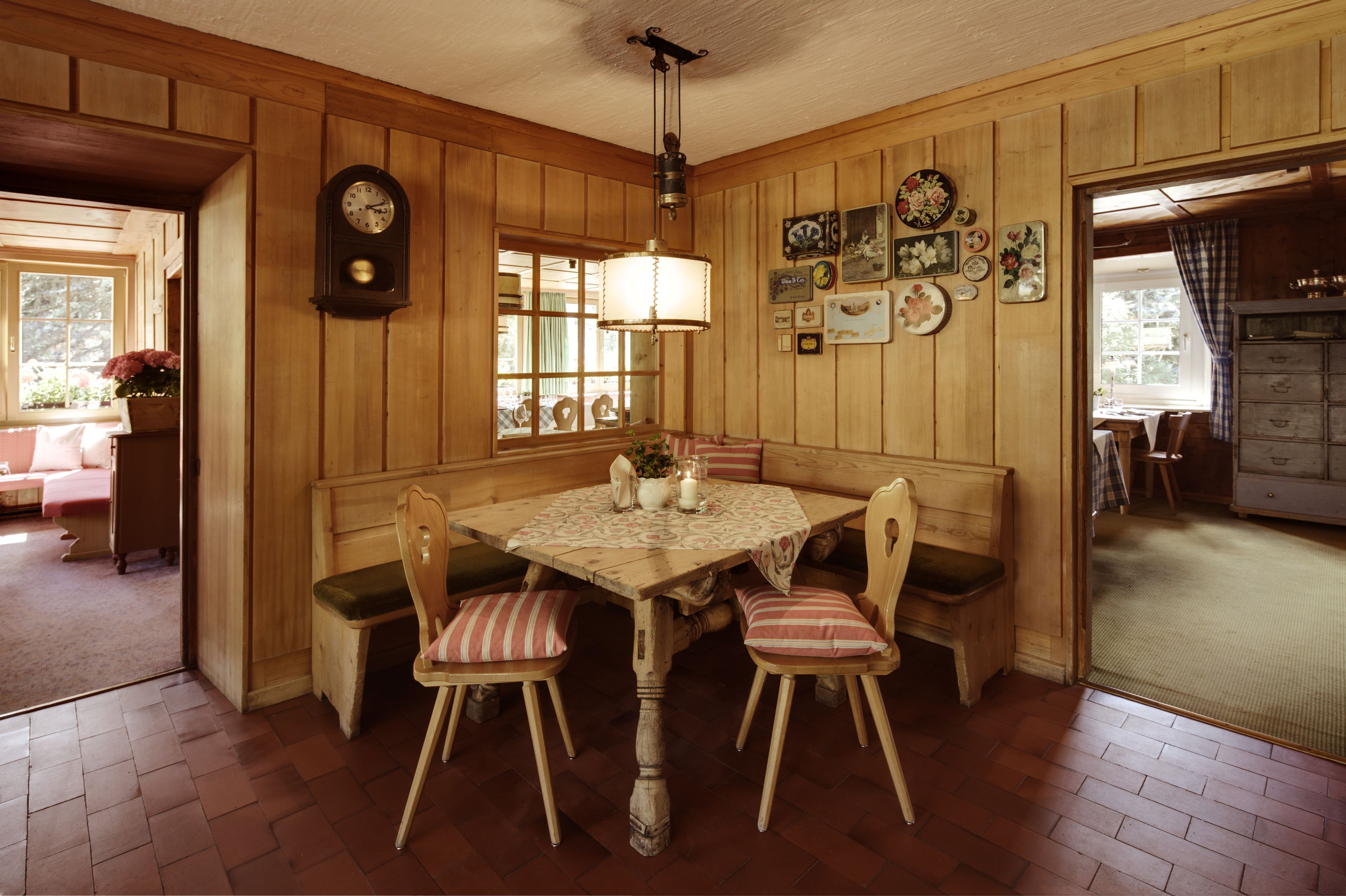 Comedor con paneles de madera, una mesa redonda, sillas y un reloj en la pared.