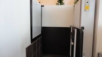 A narrow stairway leading to a dark room, with a small Christmas tree and a caution sign on a utility box.