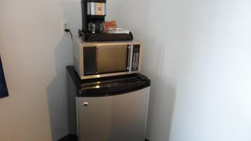 Une petite cuisine équipée d’un four à micro-ondes et d’une machine à café, le tout installé sur un plan de travail noir.