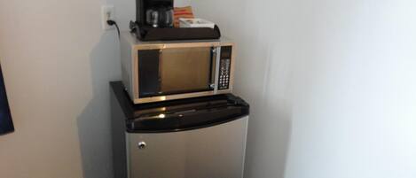 Uma cozinha compacta com micro-ondas e cafeteira em bancada preta.