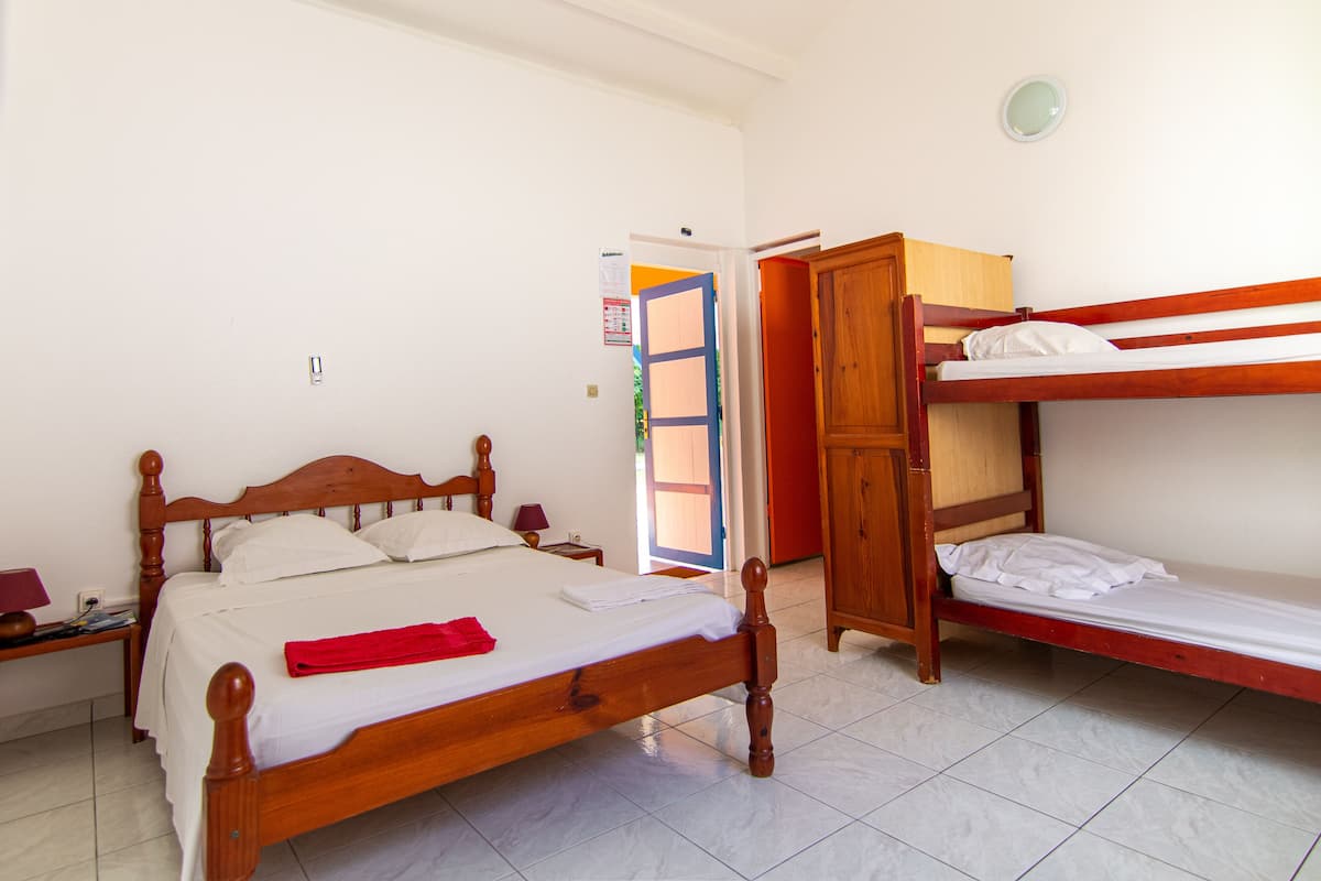 Ein Schlafzimmer mit einem hölzernen Bett, einem Etagenbett und einem kleinen Schreibtisch mit Lampe.