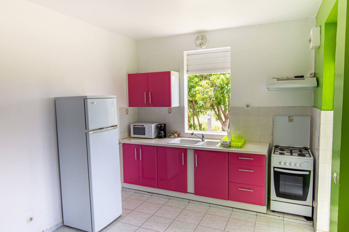 Eine kleine Küche mit Kühlschrank, Mikrowelle, Spüle und Herd.