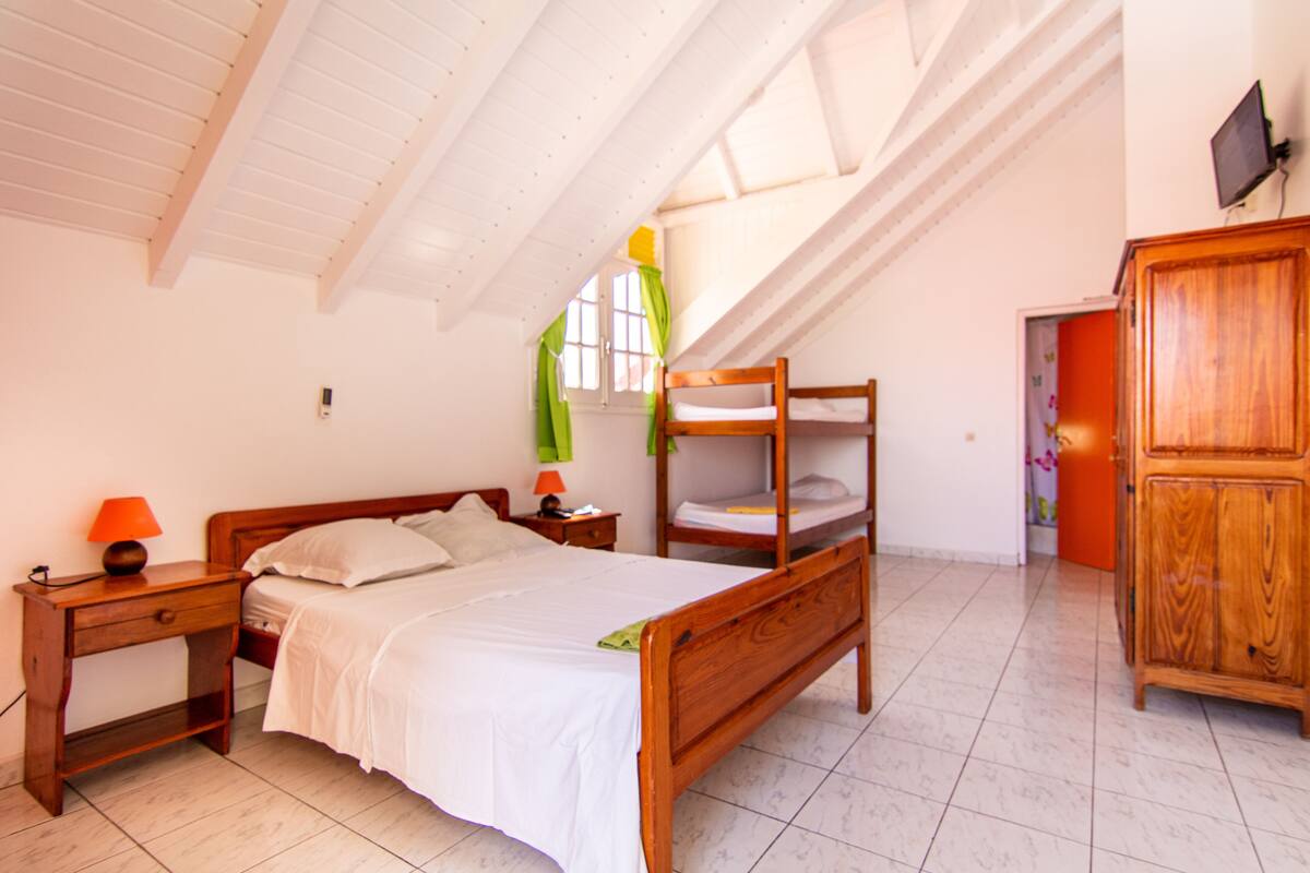 Ein Schlafzimmer mit einem hölzernen Bett, einem Nachttisch, einem Schreibtisch und einem Kleiderschrank.