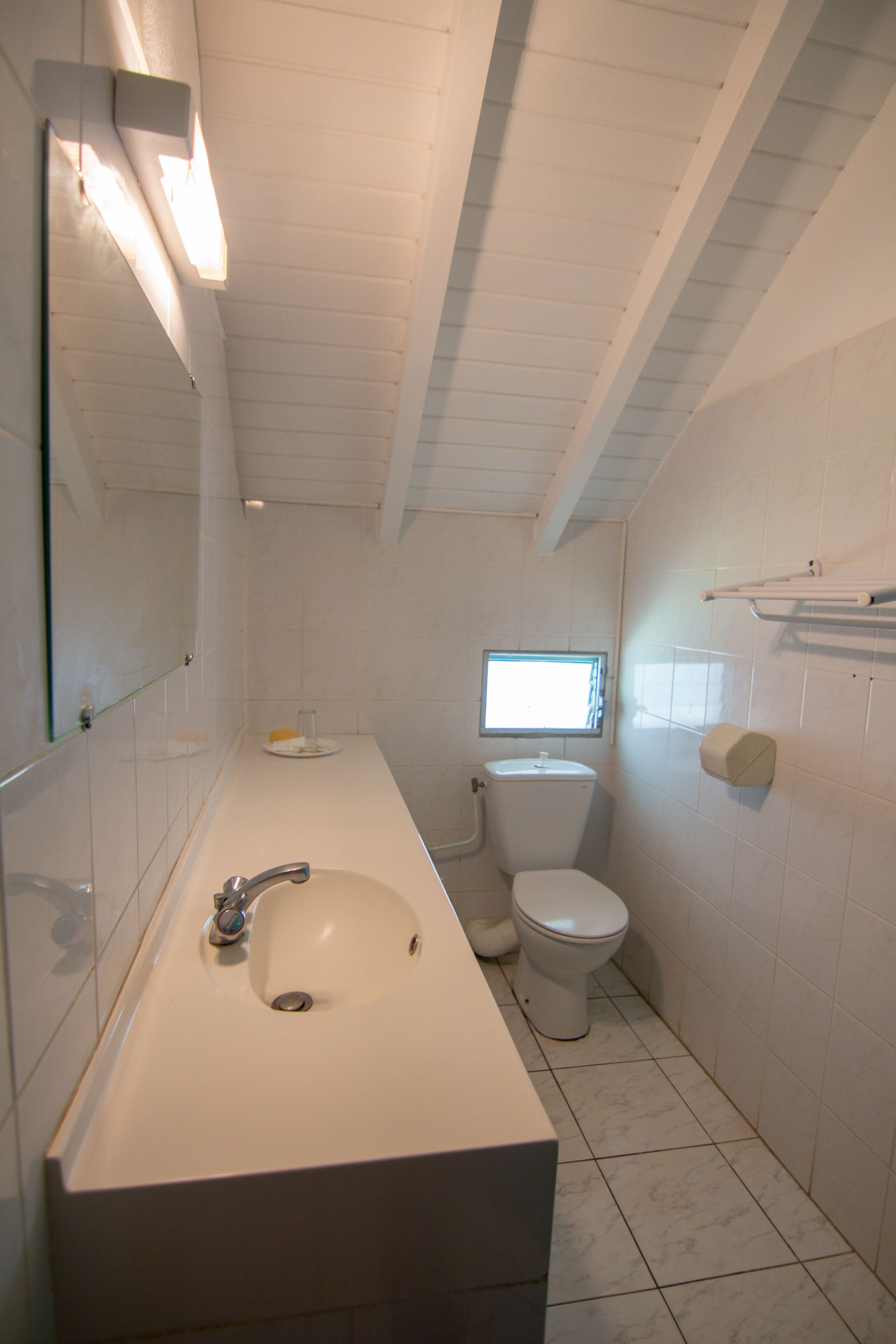 A bathroom with a sink, toilet, and a window.