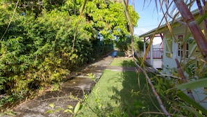 A pathway leading to a house surrounded by lush greenery. - Au Jardin Debeauséjour (Capesterre-de-Marie-Galante)