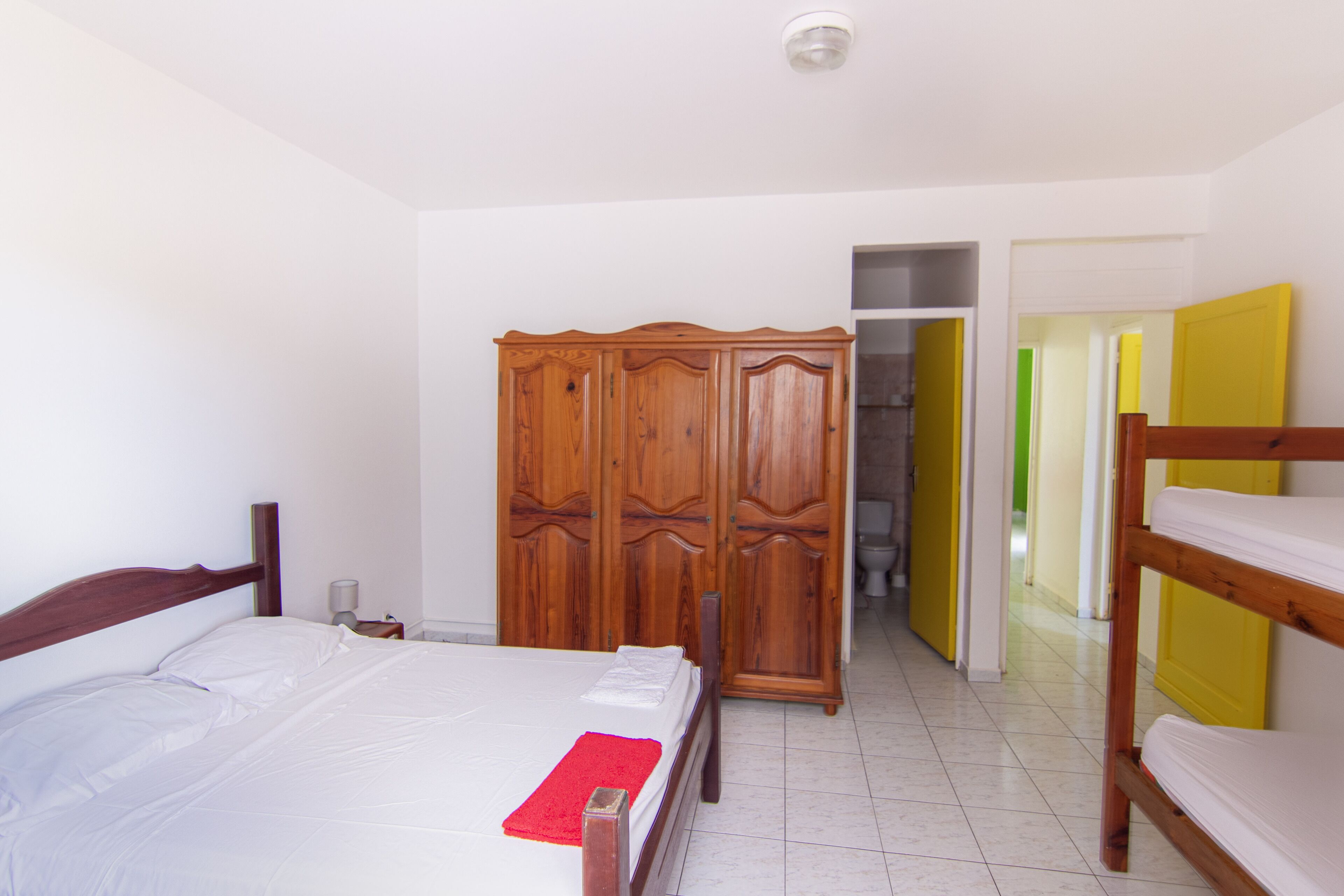 A bedroom with a bed, a wardrobe, and a bunk bed.