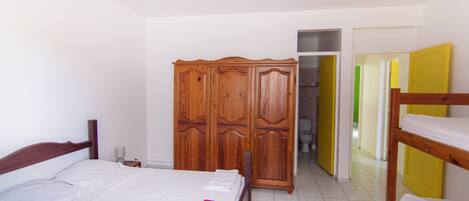 A bedroom with a bed, a wardrobe, and a bunk bed.