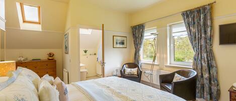 A bedroom with a bed, a chair, a dresser, a window with curtains, and a radiator.