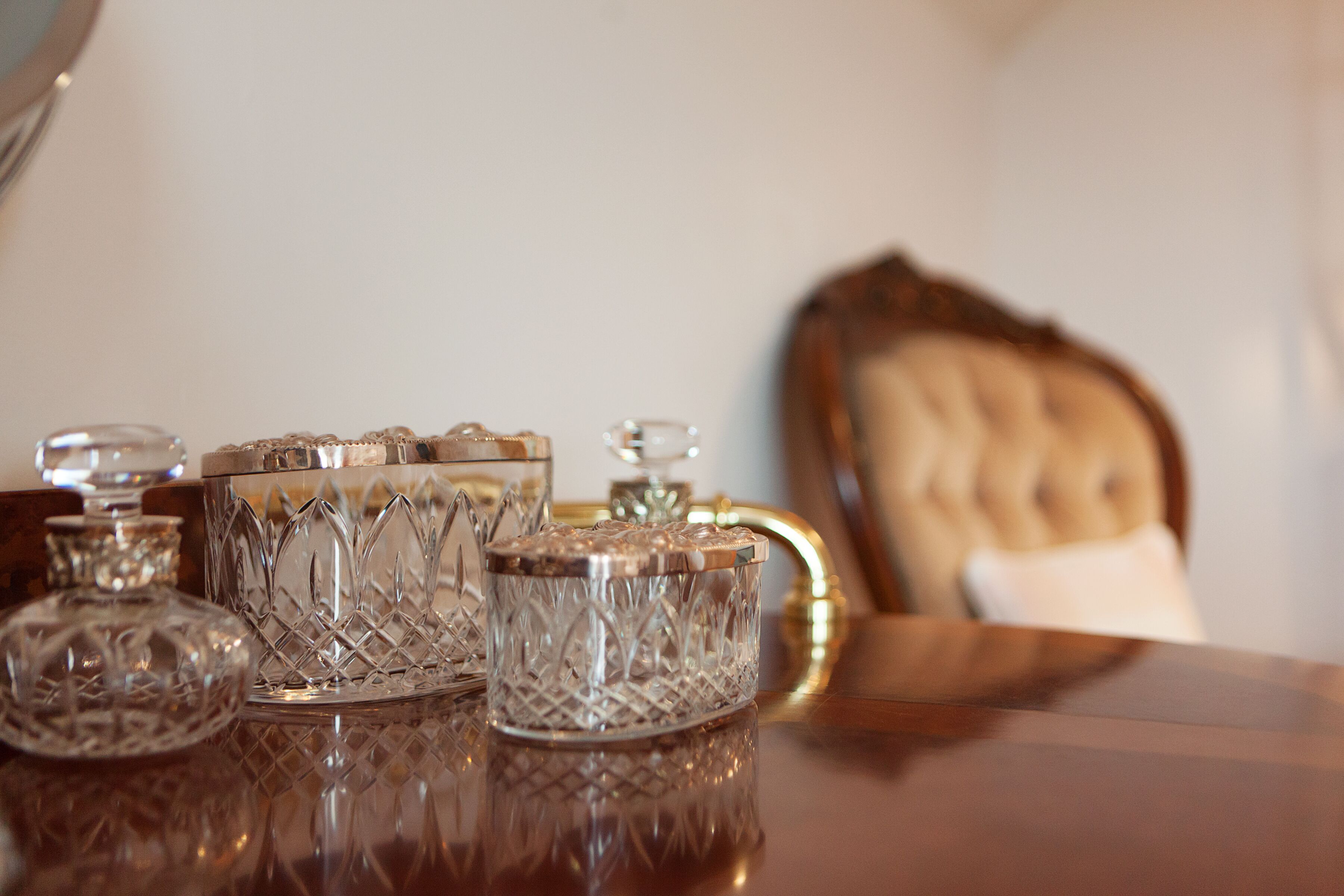 A table with crystal decanters and a glass pitcher. A chair is partially visible in the background.