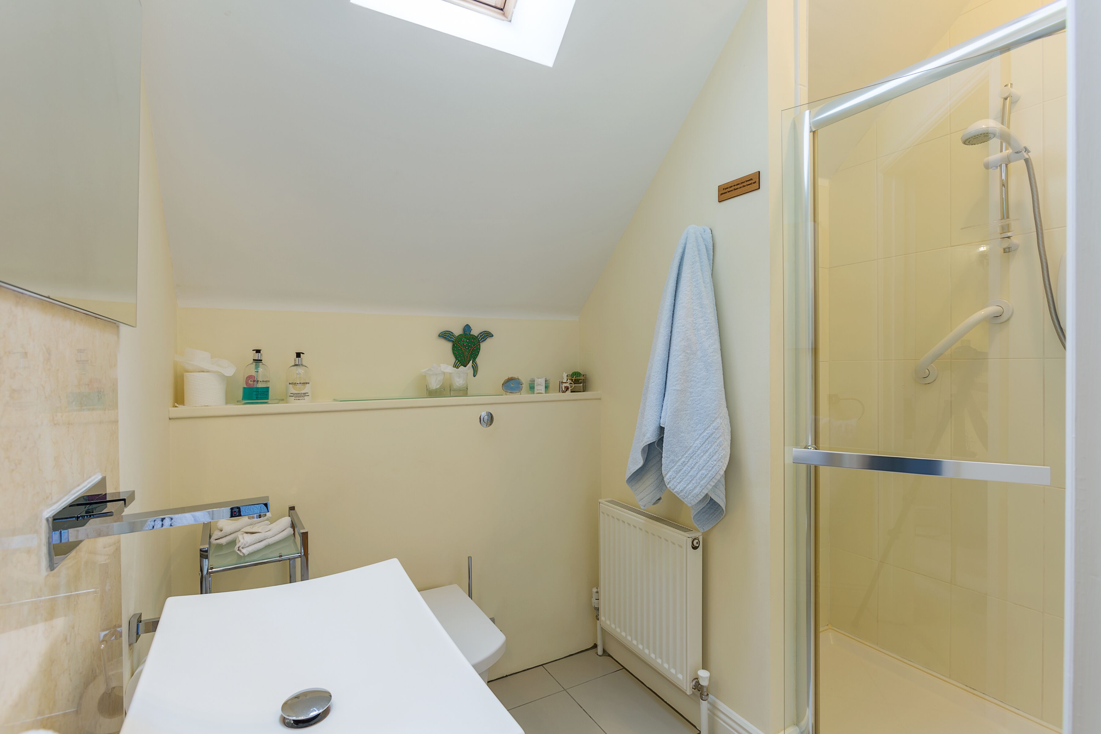Een badkamer met een douche, een wastafel en een handdoekhouder.