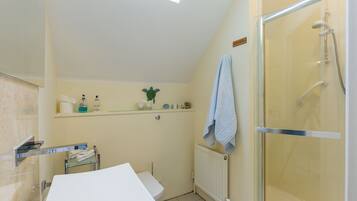 Een badkamer met een douche, een wastafel en een handdoekhouder.
