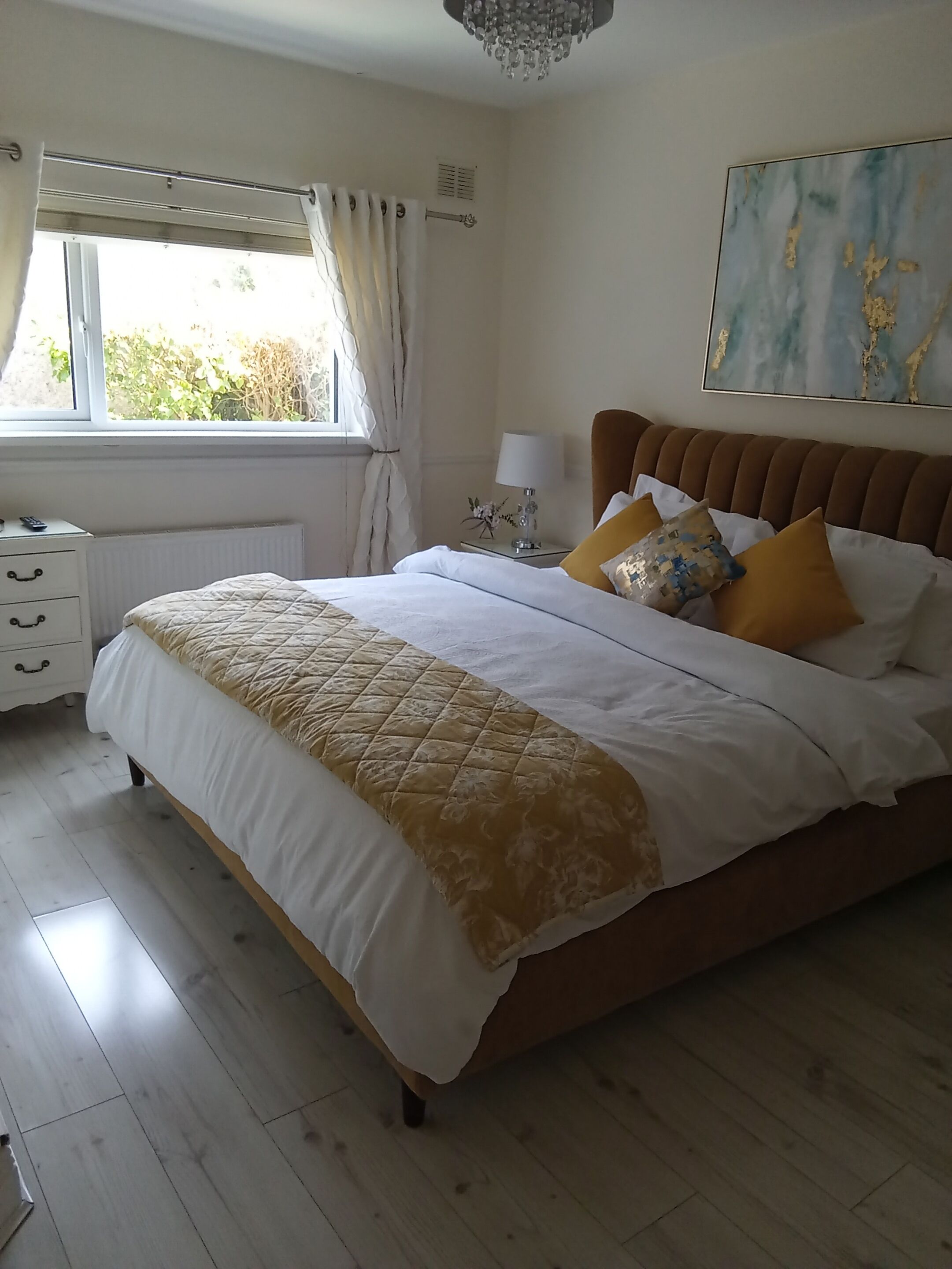 Una camera da letto con un letto, un comodino, una lampada e una finestra con tende.