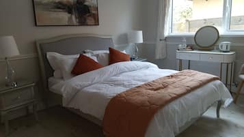 Un lit bien fait, avec des oreillers, une table de chevet avec une lampe, une commode avec un miroir et une fenêtre avec des rideaux.