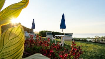 Un patio con sillas blancas y sombrillas azules, con vista a un cuerpo de agua.