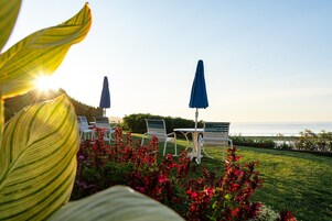 Un patio con sillas blancas y sombrillas azules, con vista a un cuerpo de agua.