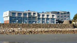 A multi-story hotel with a stone retaining wall in front. - The Cutty Sark Motel (York Beach)