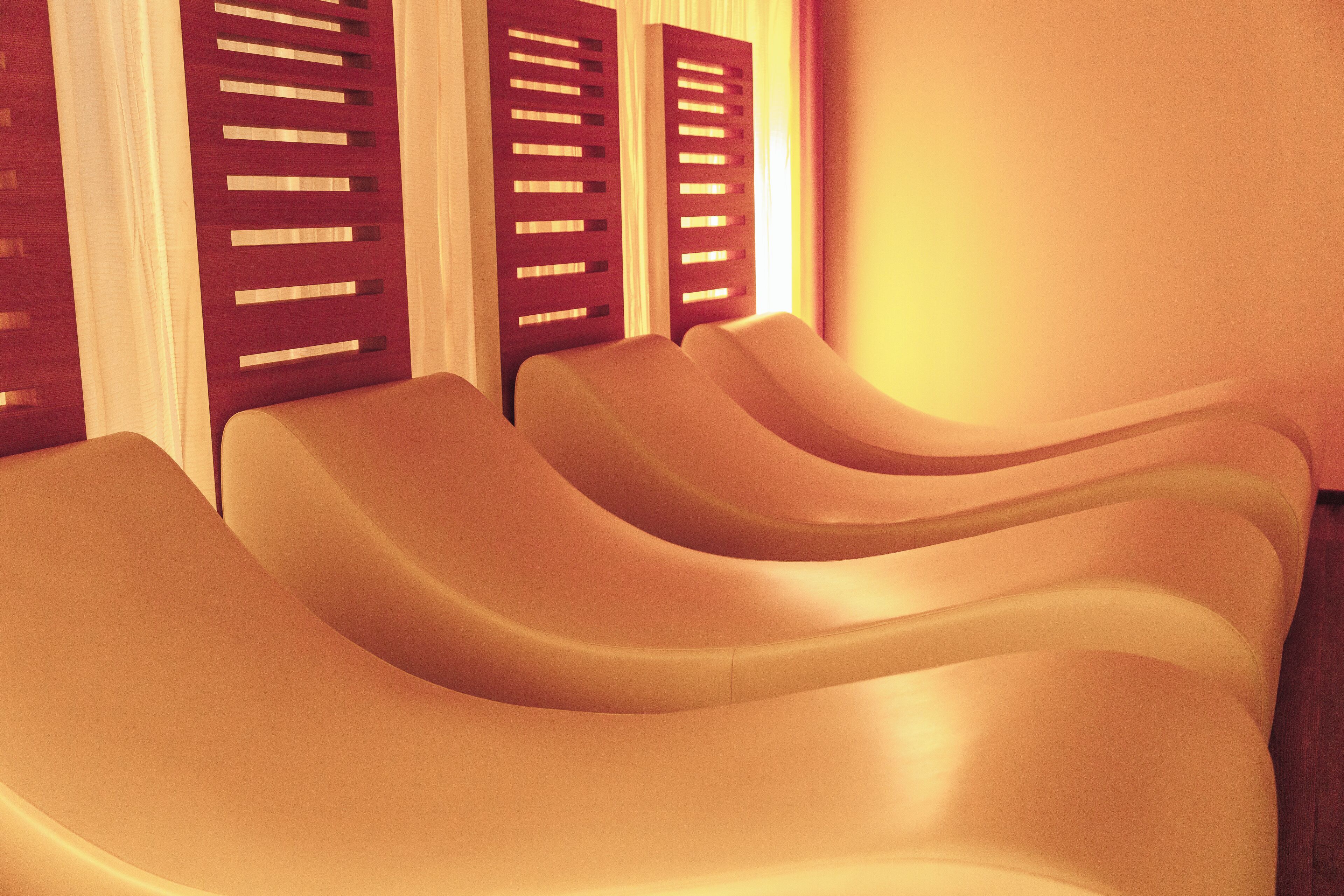A row of curved, cream-colored chairs in a room with wooden slatted walls and a warm light.