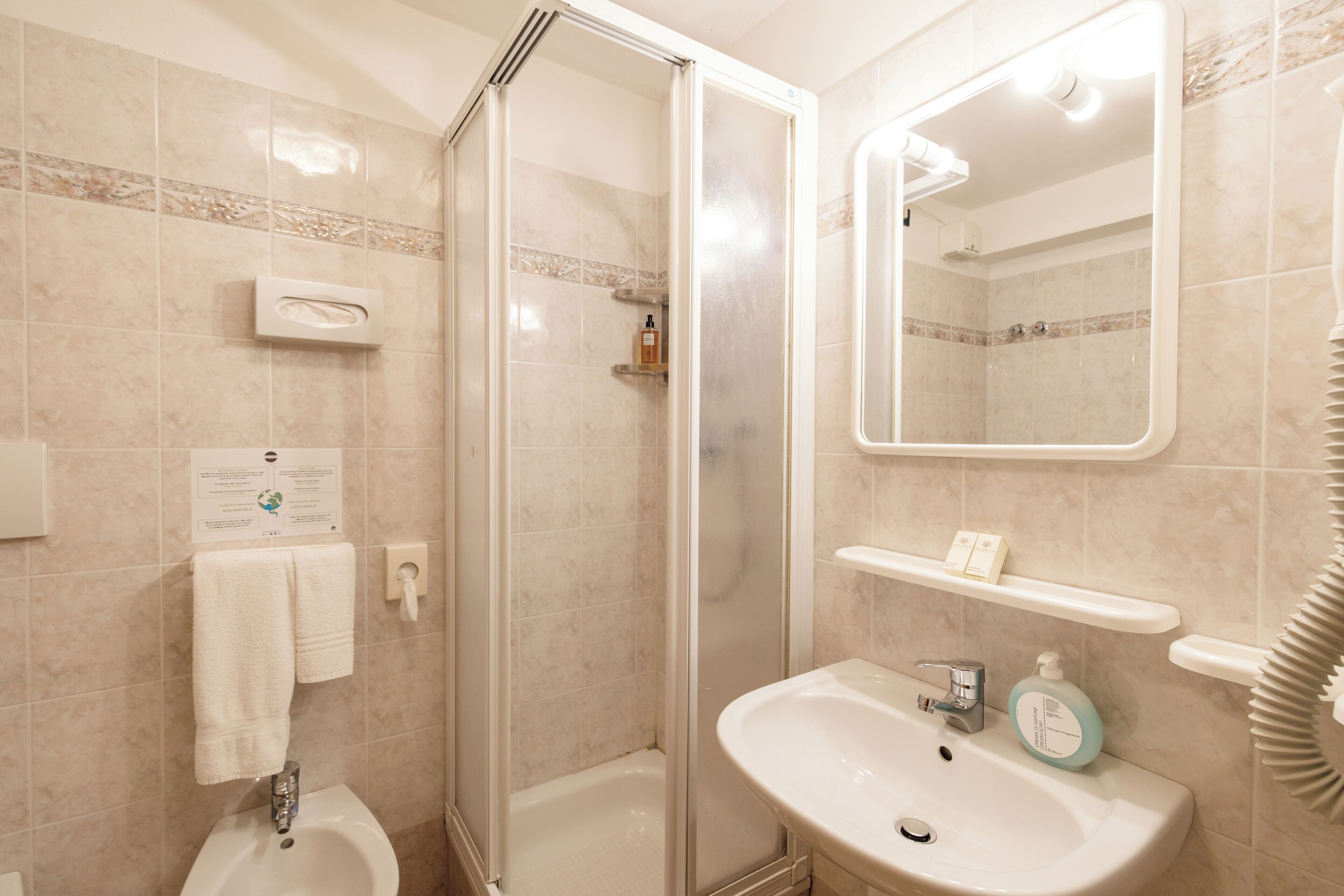 Een badkamer met een douchecabine van glas, een wastafel met spiegel en een toilet.