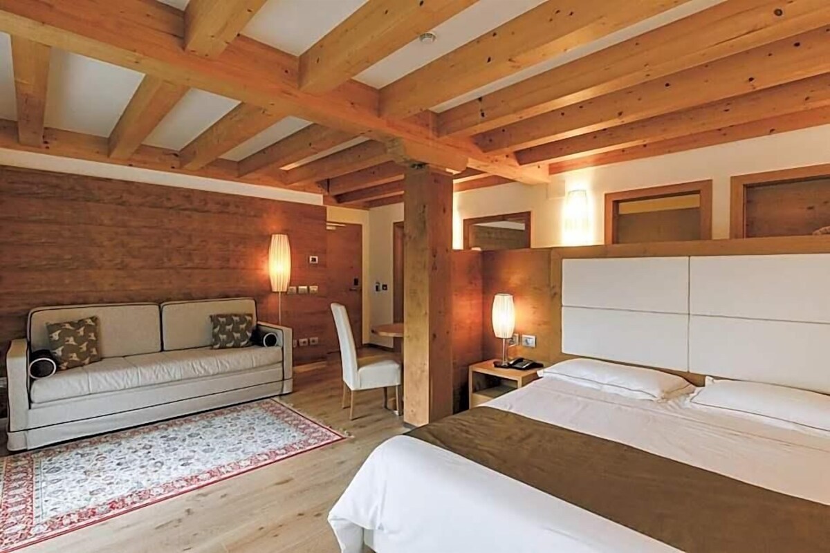 Une pièce comprenant un lit, un canapé, une chaise et une table de chevet avec une lampe.