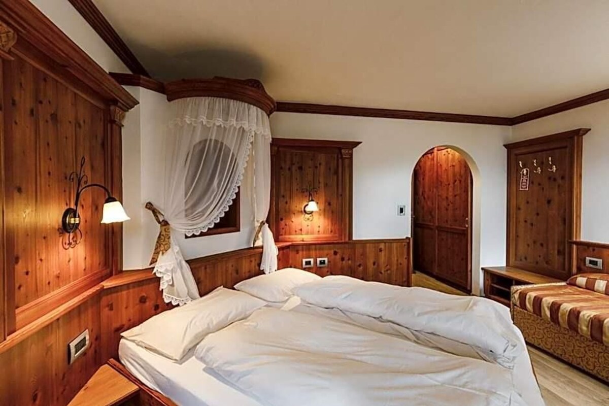 Ein Schlafzimmer mit Holzwandverkleidung, einem großen Bett, einem Baldachin und einem Kleiderschrank.