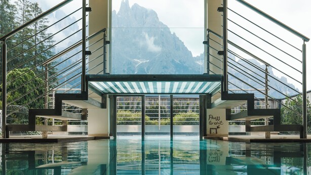 Ein Pool mit Bergblick, eine Treppe mit Glasgeländern und ein Schild mit der Aufschrift 'Press to exit'.
